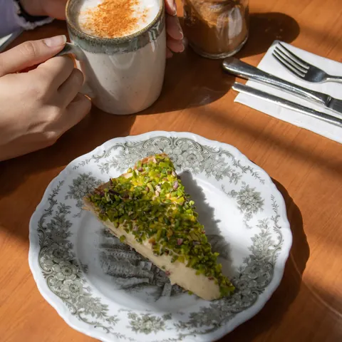 Pistachio cake and a cinnamon cappuccino in the afternoon sun