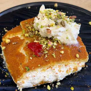 A square of kunafa with ashta cream and pistachios