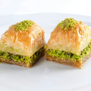 Two pieces of pistachio baklava on a white plate
