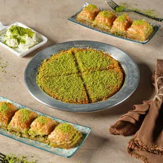 A table with pistachio kunafa, baklava and cream