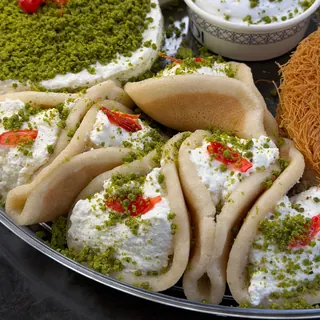 Qatayef filled with cream and pistachio on a tray