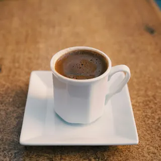 A small cup of Arabic coffee on a square saucer